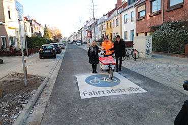 Senatorin Schaefer, Herr Schmauder (ASV) und Ortsamtsleiter Herr Hermening nutzen einen der neuen Bügel für Lastenräder im Alten Postweg