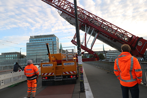 Das Spezialfahrzeug fährt die Plattform zwischen zwei Lichtmasten aus.